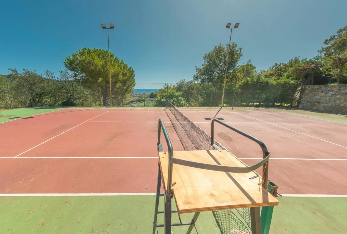 Campo da tennis circondato dal verde con vista sul mare