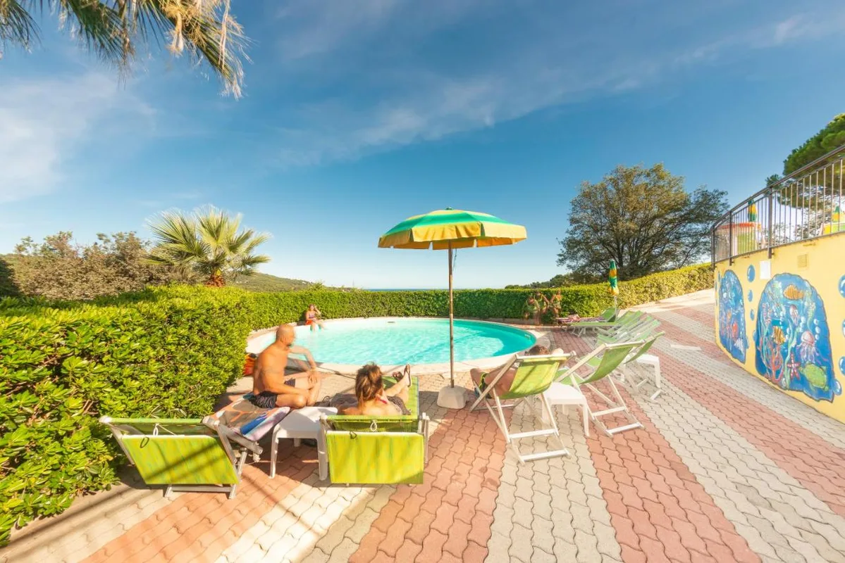 Piscina rotonda con ospiti in relax su lettini e ombrellone colorato