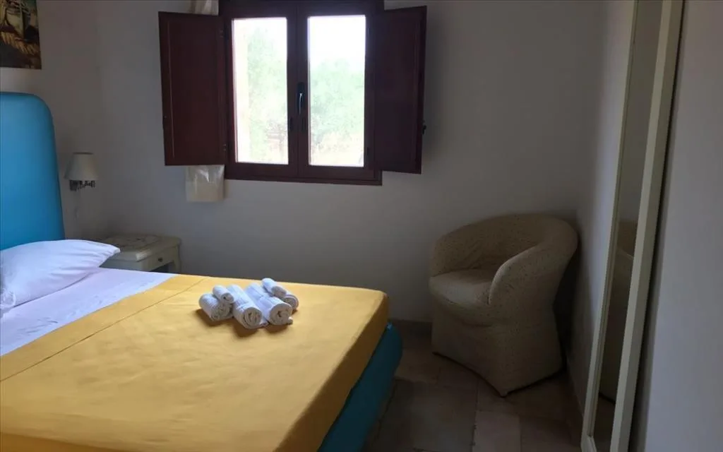 Camera con poltrona, finestra con persiane e vista sul verde