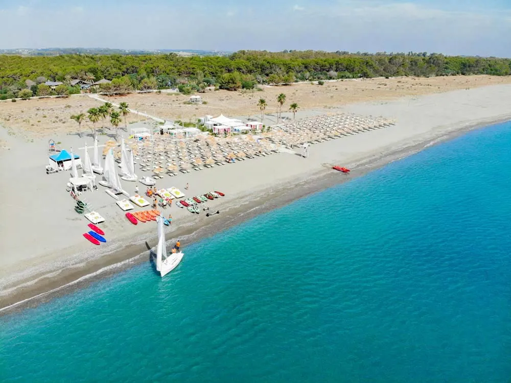 Vista aerea della spiaggia attrezzata con ombrelloni e sport acquatici sul mare turchese