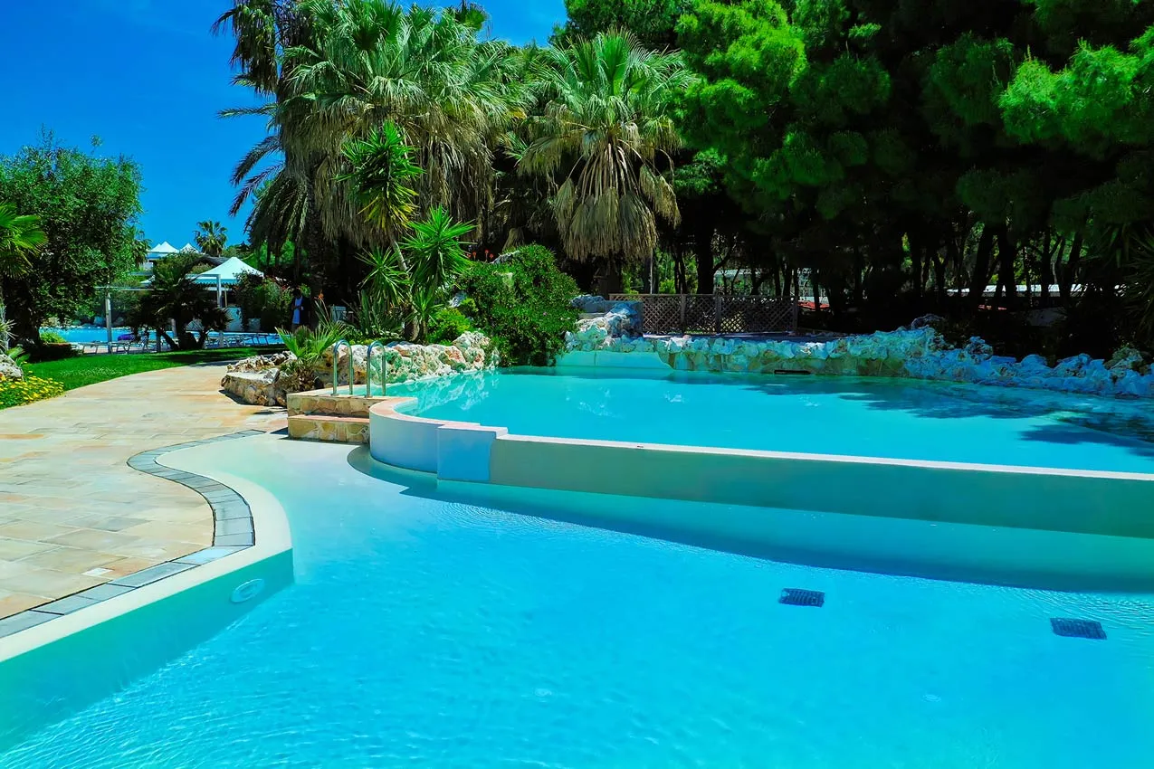 Piscina laguna con acqua turchese, cascata in roccia e vegetazione tropicale