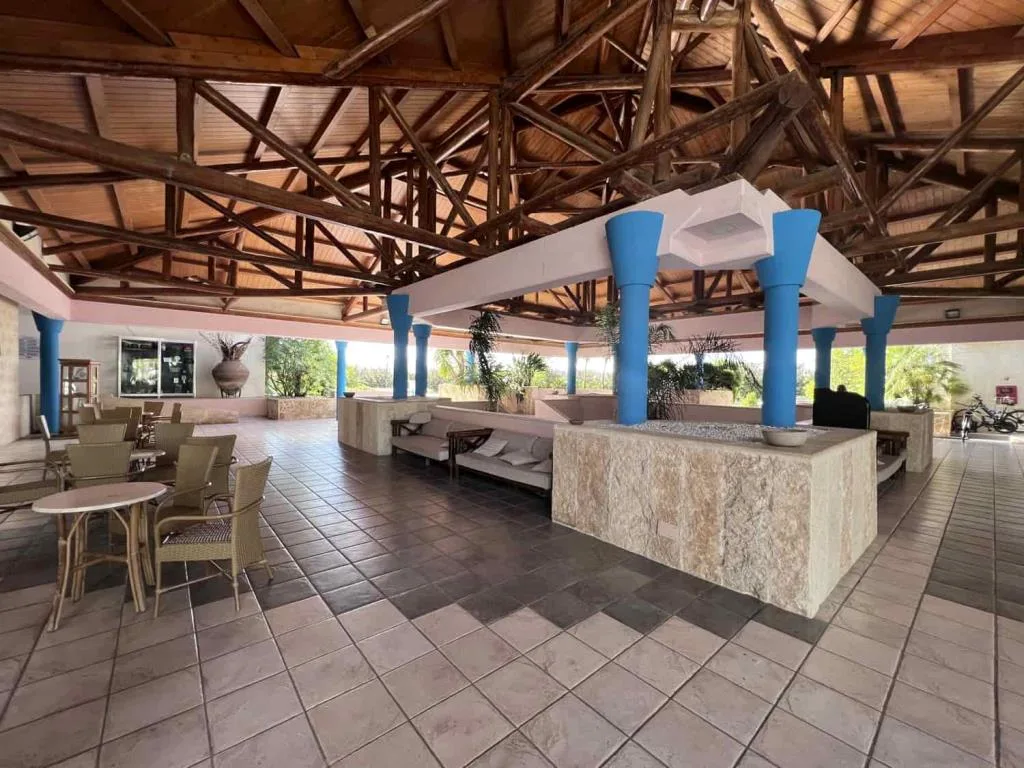 Ampia hall coperta con tetto in legno, colonne blu e area lounge con divani