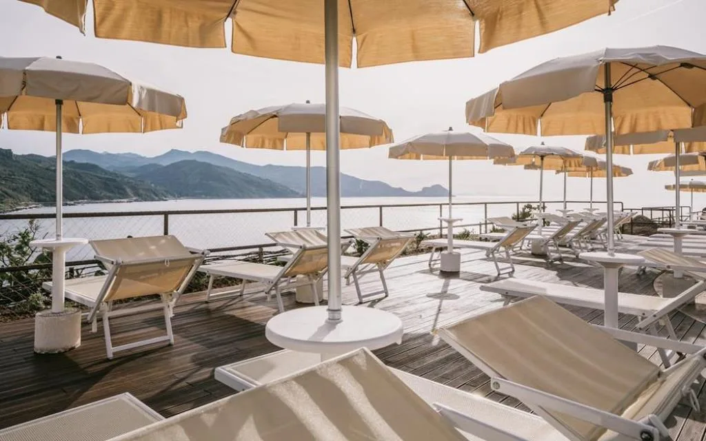 Solarium con lettini e ombrelloni gialli su terrazza in legno vista mare