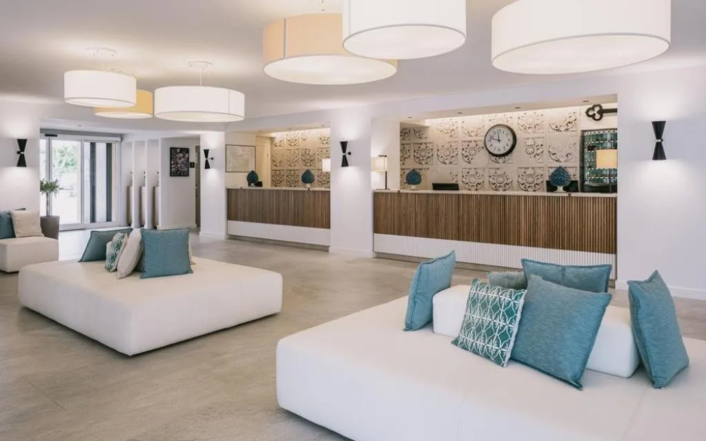 Hall dell'hotel con reception in legno, divani bianchi e cuscini turchesi