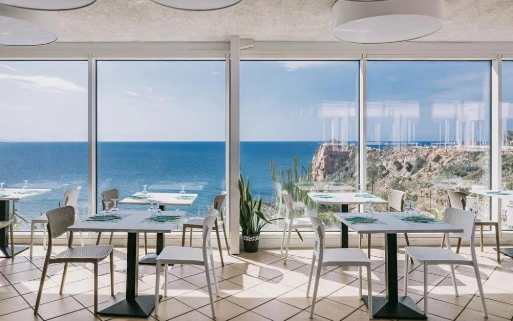 Sala ristorante interna con ampie vetrate affacciate sul mare e la costa