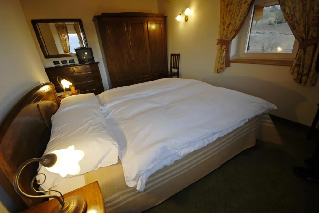 Camera con letto matrimoniale, armadio in legno scuro e finestra con vista