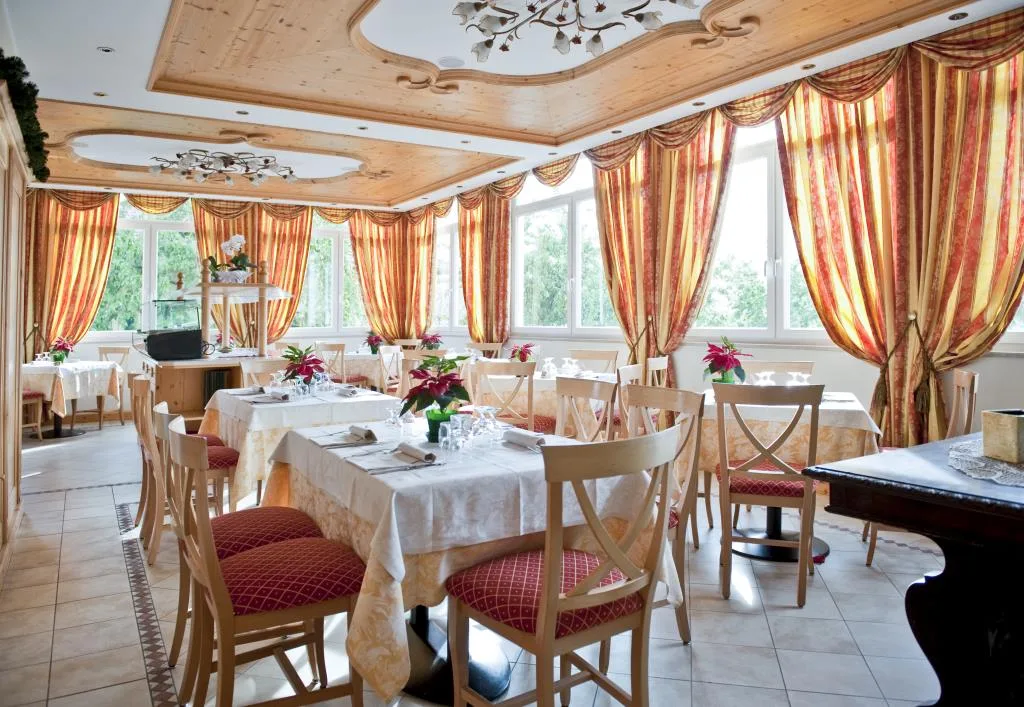 Sala ristorante elegante con tende dorate e tavoli apparecchiati