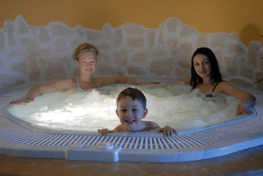 Famiglia sorridente nella vasca idromassaggio della spa
