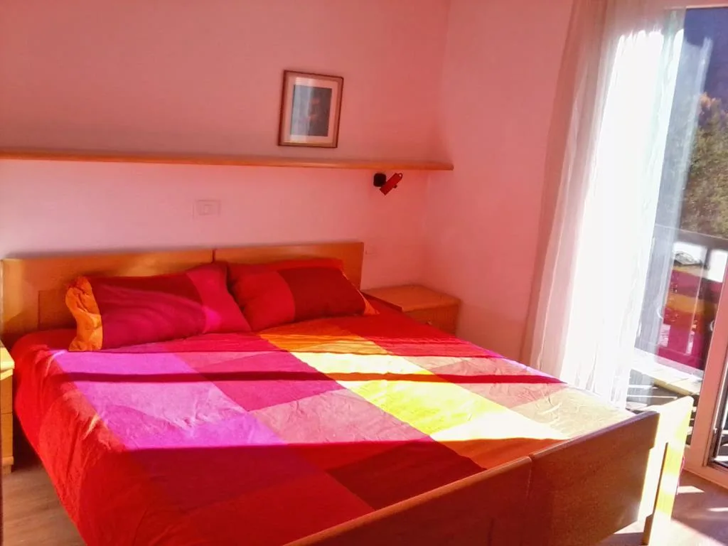 Camera con letto matrimoniale e copriletto colorato illuminata dalla luce naturale