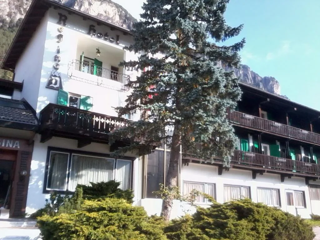 Esterno dell'hotel con abete in primo piano e montagne sullo sfondo