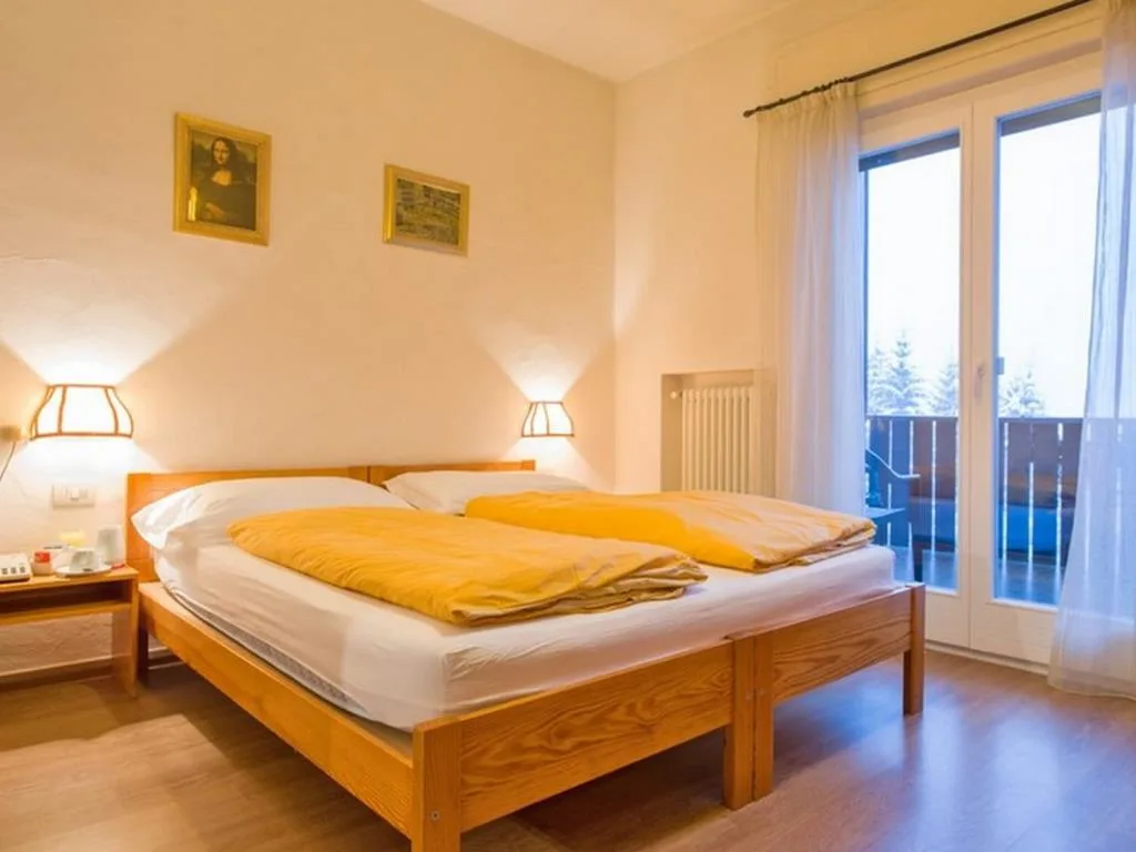 Camera luminosa con letto matrimoniale, coperte gialle e porta-finestra sul balcone