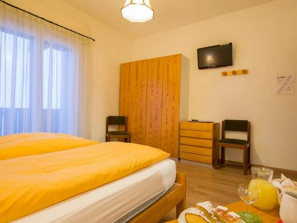 Camera con letto, armadio in legno, TV a parete e colazione servita
