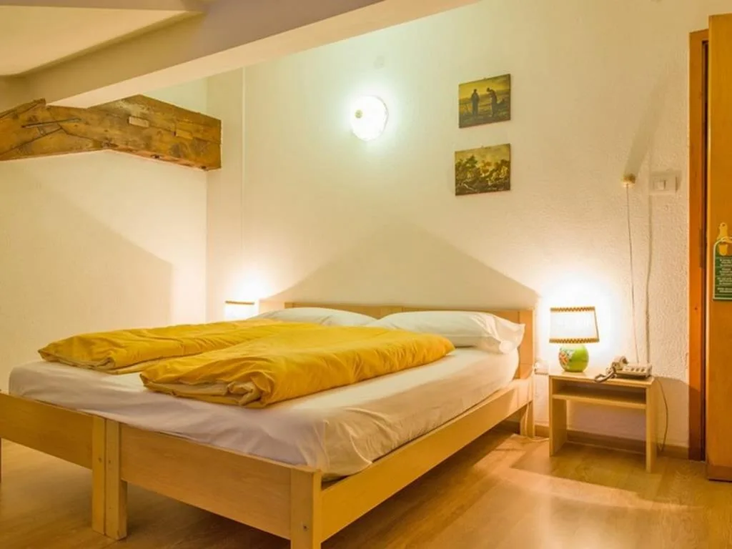 Camera mansardata con letto matrimoniale, coperta gialla e travi a vista