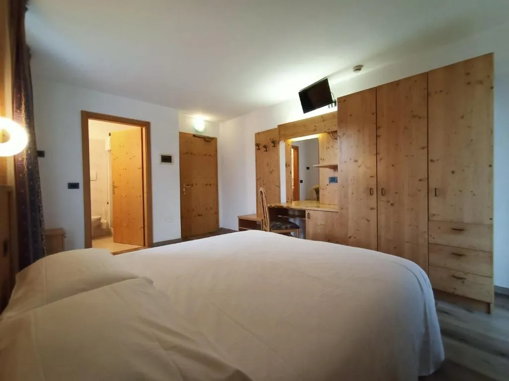 Camera matrimoniale con arredi in legno, armadio, TV e bagno privato