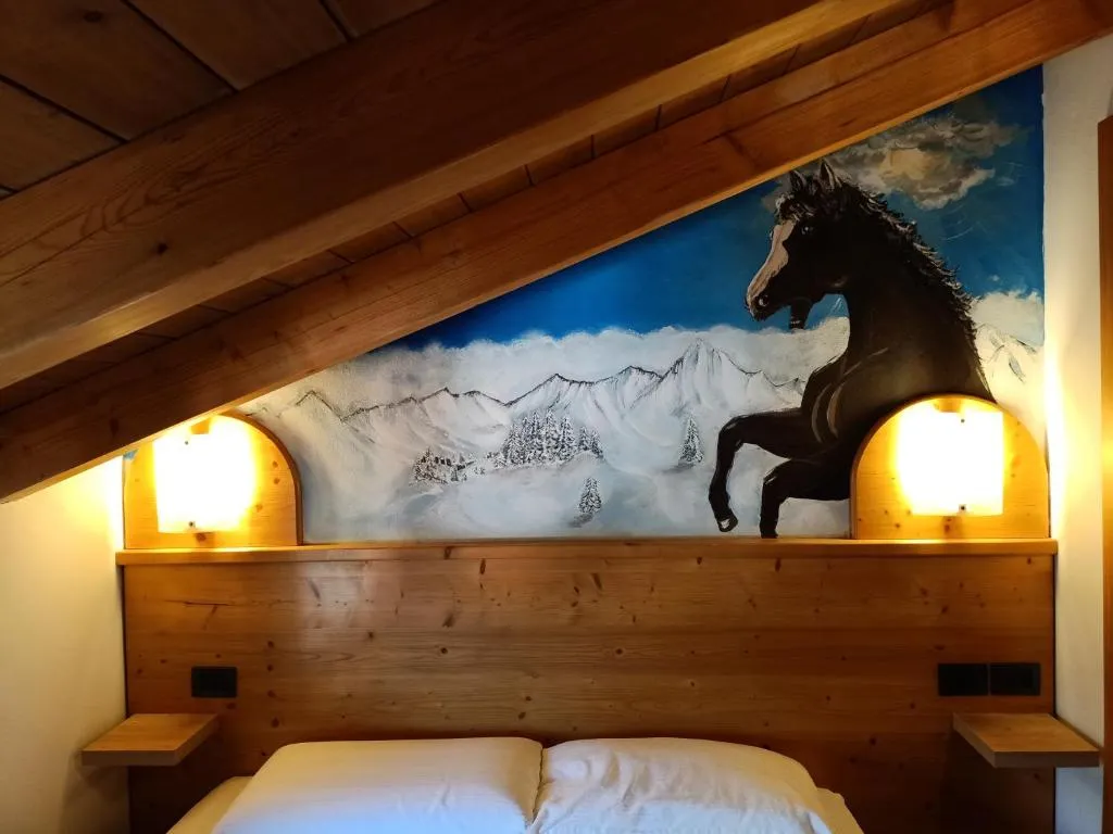 Testiera del letto con dipinto di cavallo nero e paesaggio innevato illuminata da lampade