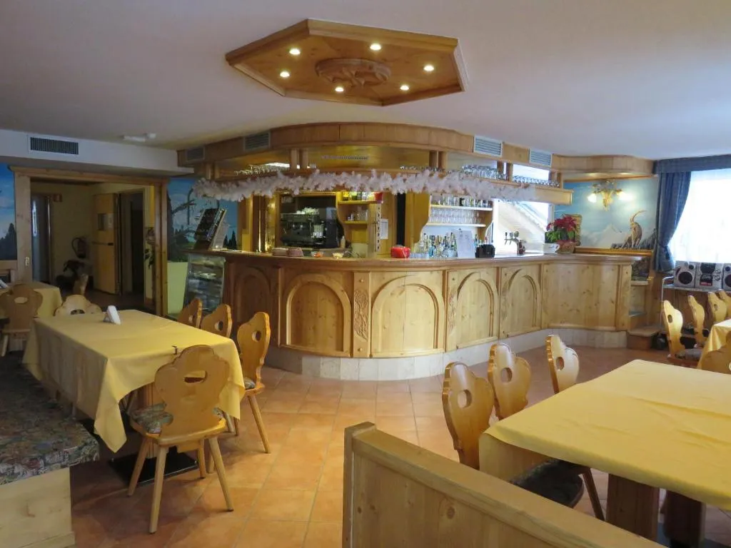 Zona bar interna con bancone in legno intagliato e tavoli con tovaglie gialle
