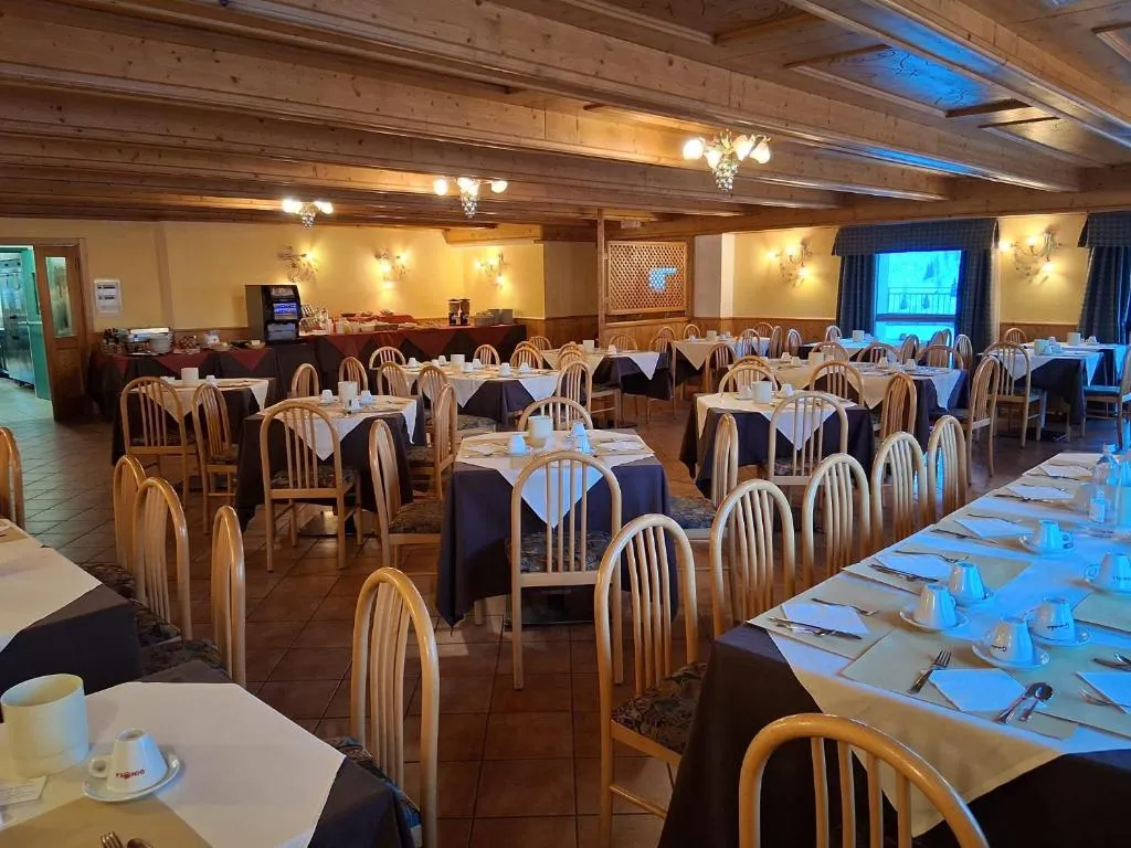Sala ristorante con soffitto in legno, tavoli apparecchiati e tovaglie scure
