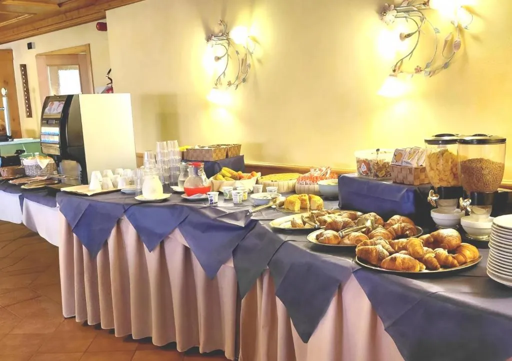 Buffet della colazione con cornetti, cereali, frutta e macchina del caffè