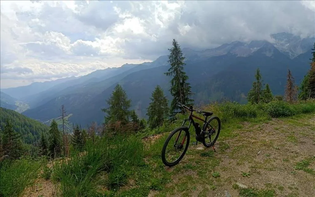 Mountain bike parcheggiata su un sentiero panoramico con vista sulle valli alpine