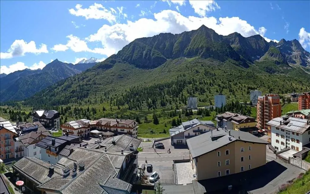 Vista panoramica del paese di montagna con tetti e imponenti cime alpine verdi