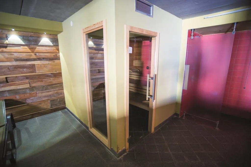 Area benessere con sauna in legno, cabina doccia e pareti colorate