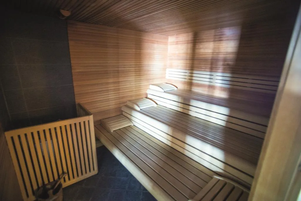 Interno di sauna finlandese in legno con panche a più livelli e luce naturale