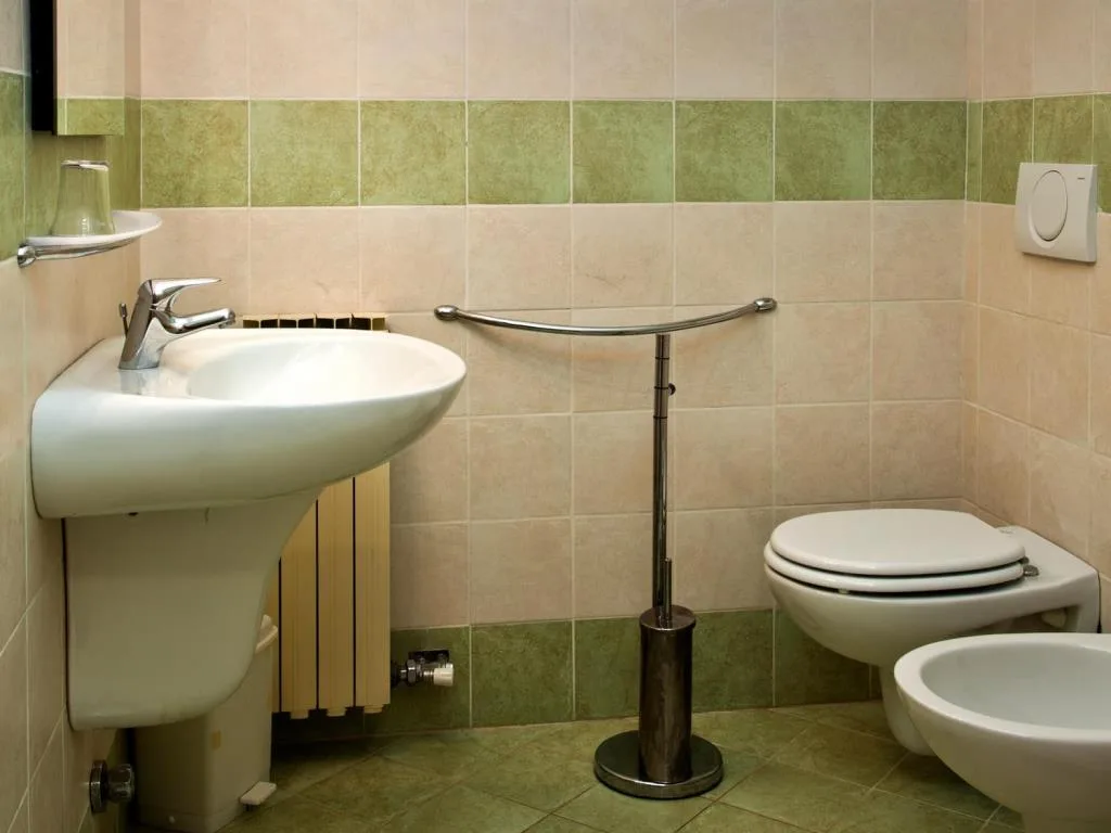 Bagno con lavabo, bidet, WC sospeso e piastrelle verdi e beige