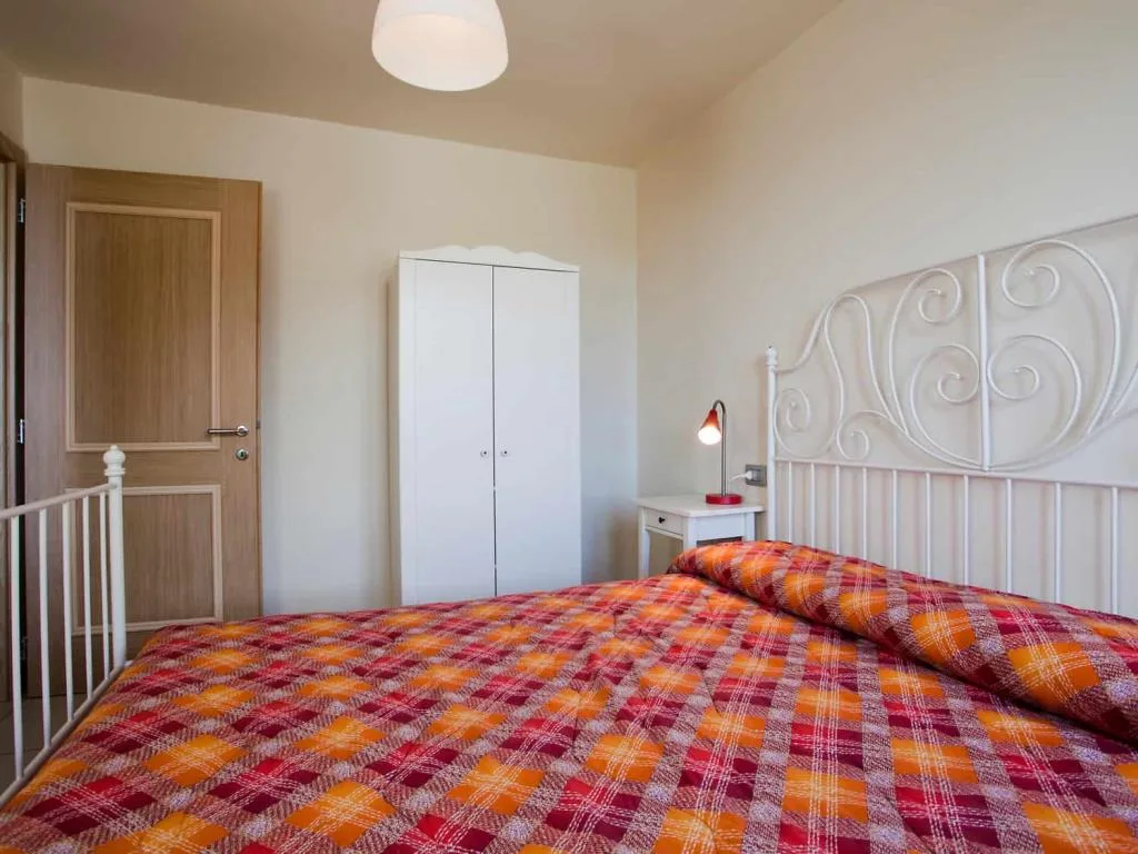 Camera da letto con letto in ferro battuto bianco, armadio bianco e coperta a quadri