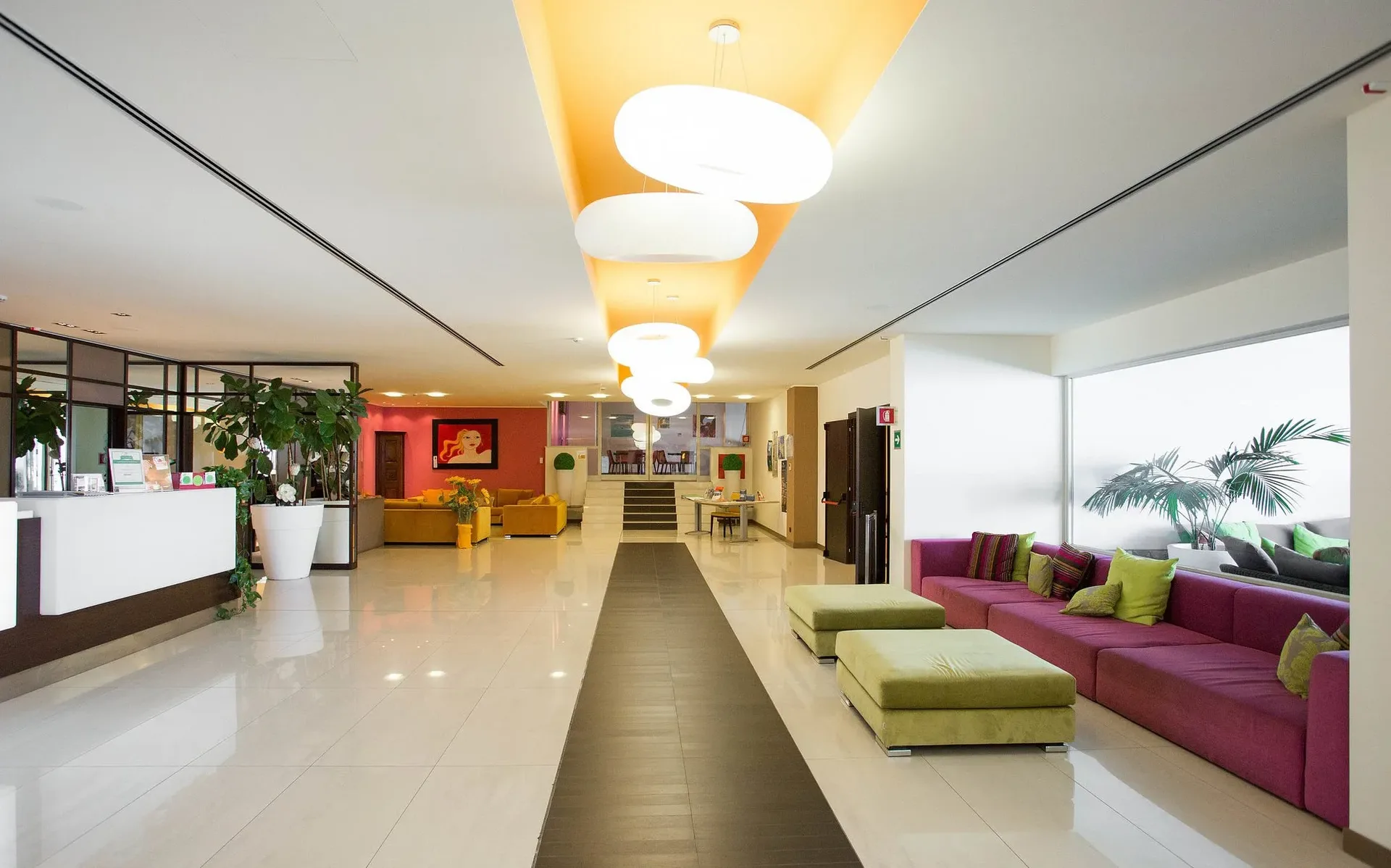 Hall moderna dell'hotel con divani colorati, piante e illuminazione di design