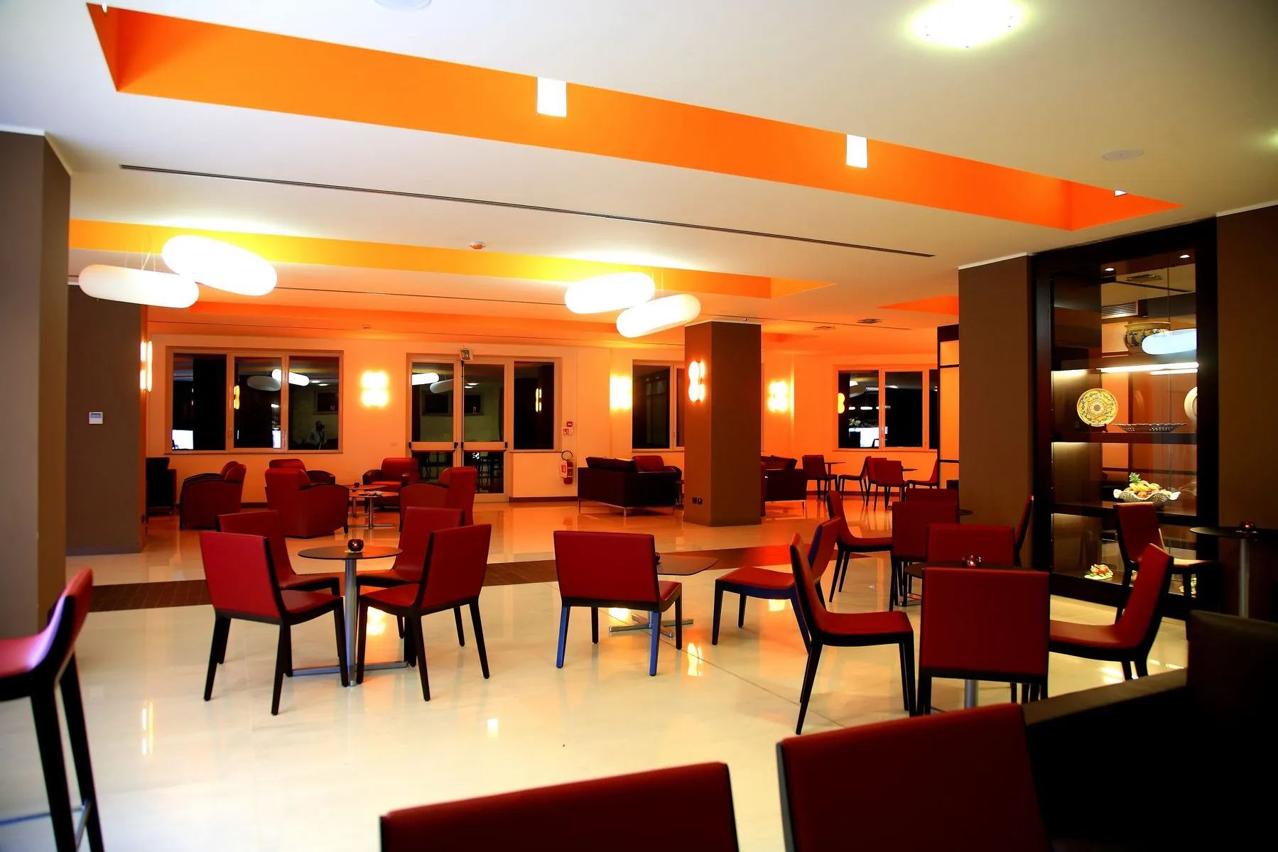 Sala lounge con poltrone rosse e illuminazione arancione di sera