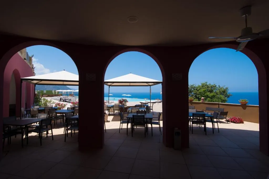 Terrazza ristorante con archi rossi affacciata su piscina e mare