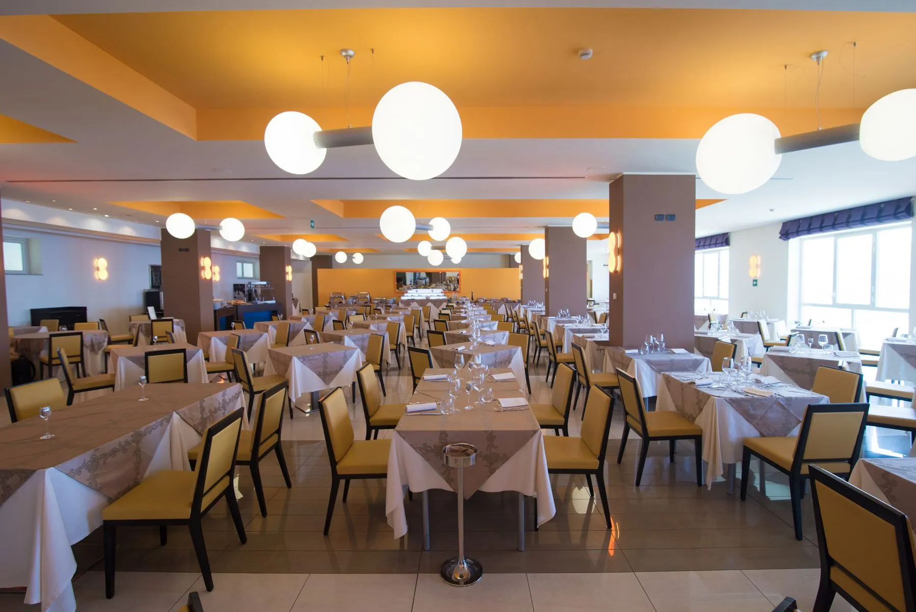 Sala ristorante interna con tavoli apparecchiati e lampade sferiche