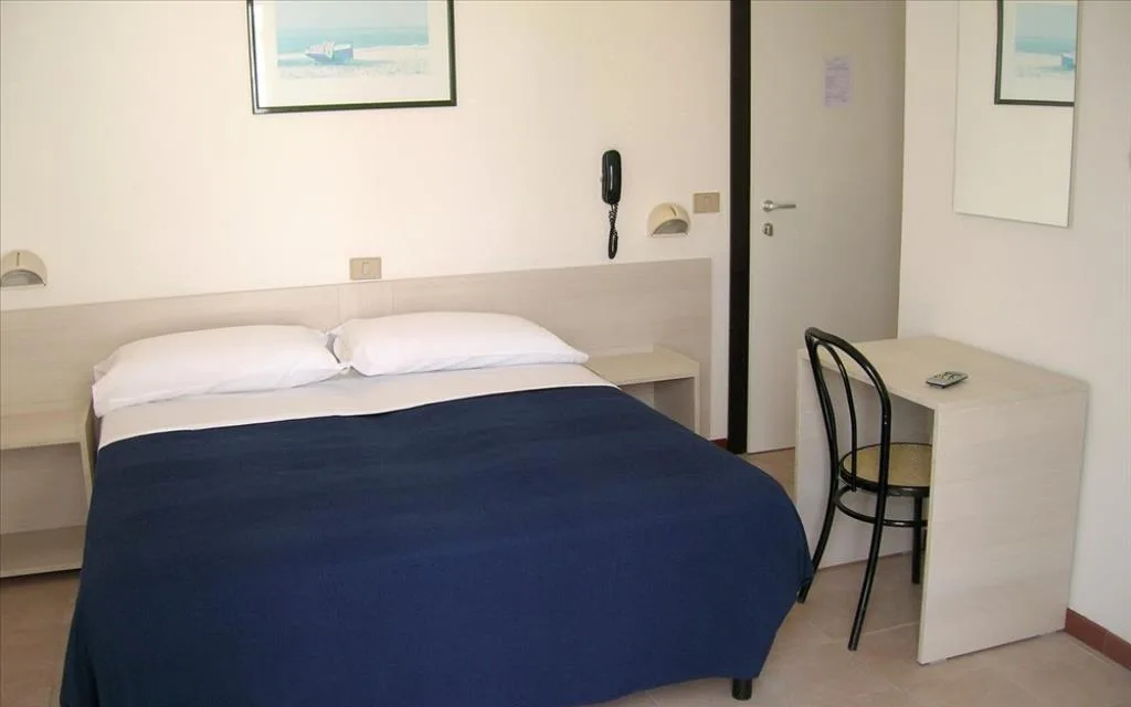 Camera doppia con letto, coperta blu e scrivania con sedia