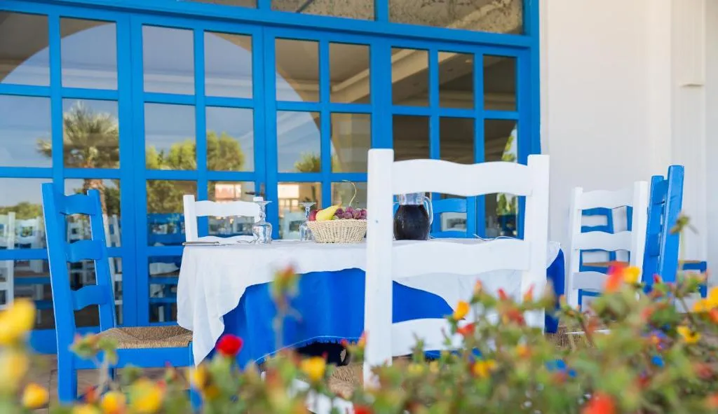 Tavolo apparecchiato all'esterno con sedie bianche e blu e fiori
