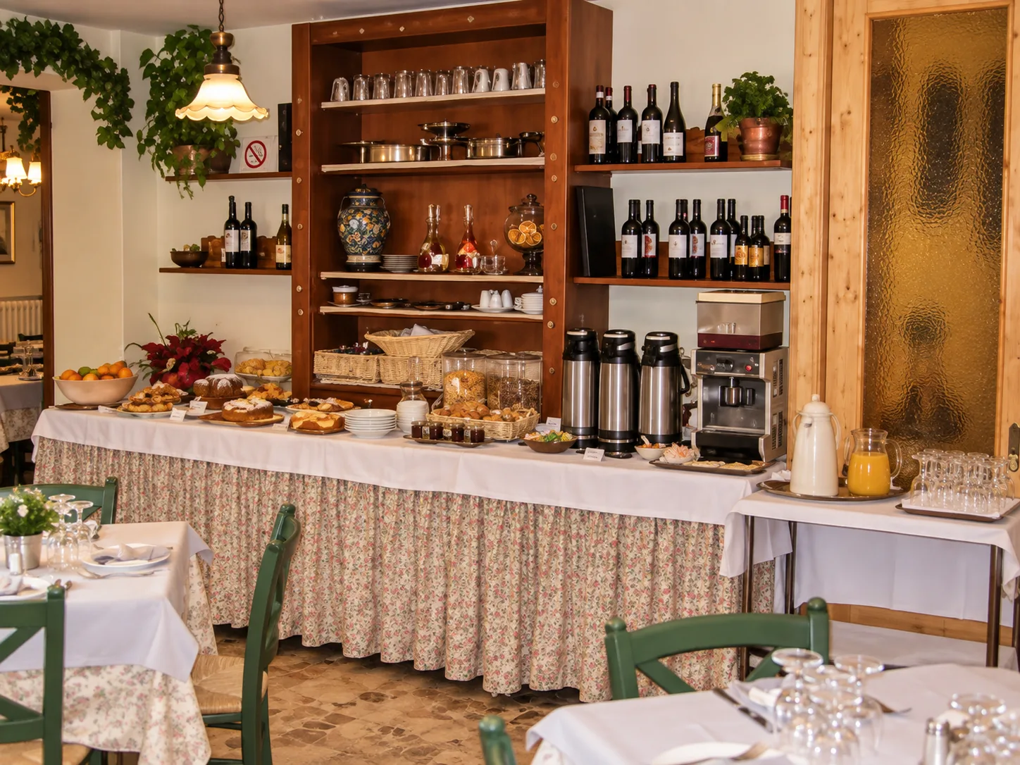 Buffet della colazione con dolci, cereali, frutta e bevande su tavolo con tovaglia a fiori