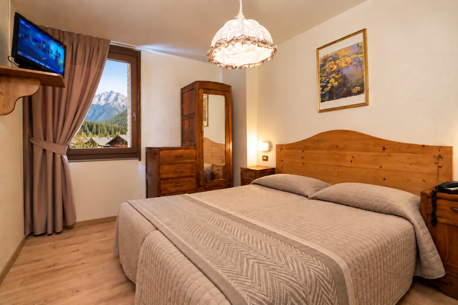 Camera da letto luminosa con vista sulle montagne innevate dalla finestra e arredo in legno