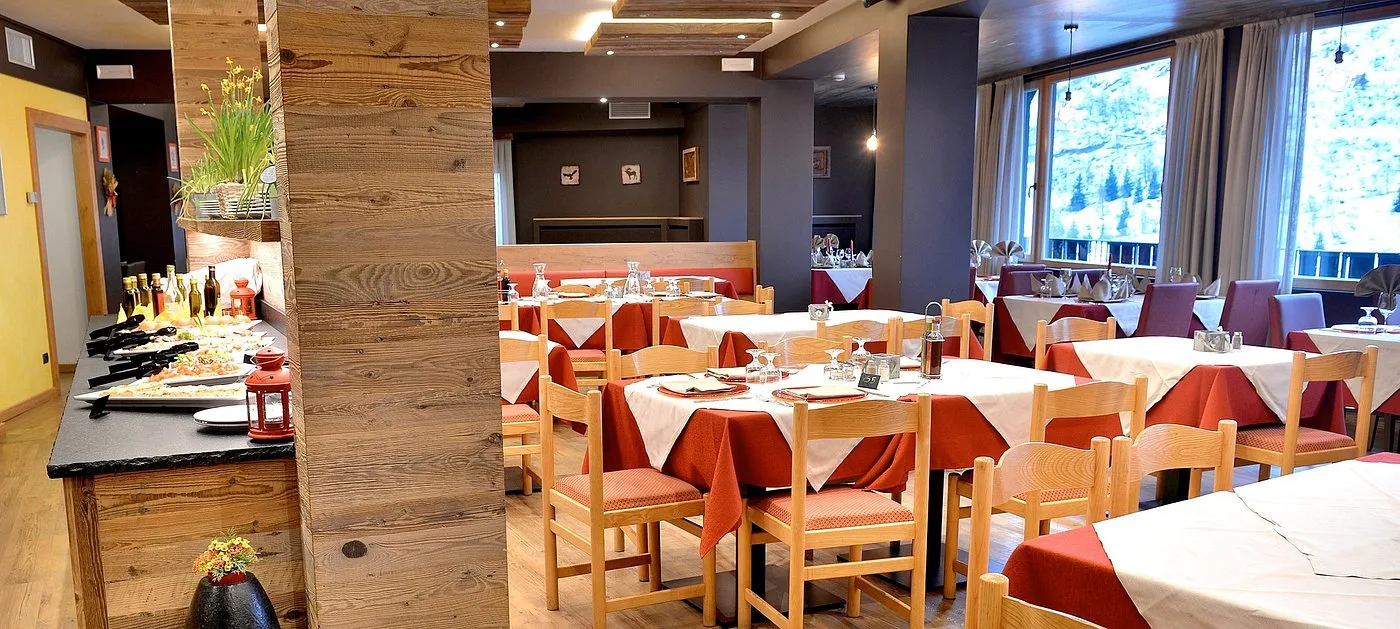 Sala ristorante con tavoli apparecchiati e buffet, vista sulla neve