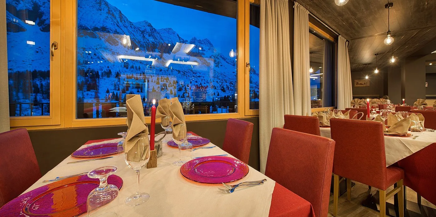 Tavolo del ristorante apparecchiato con candela e vista serale sulle montagne