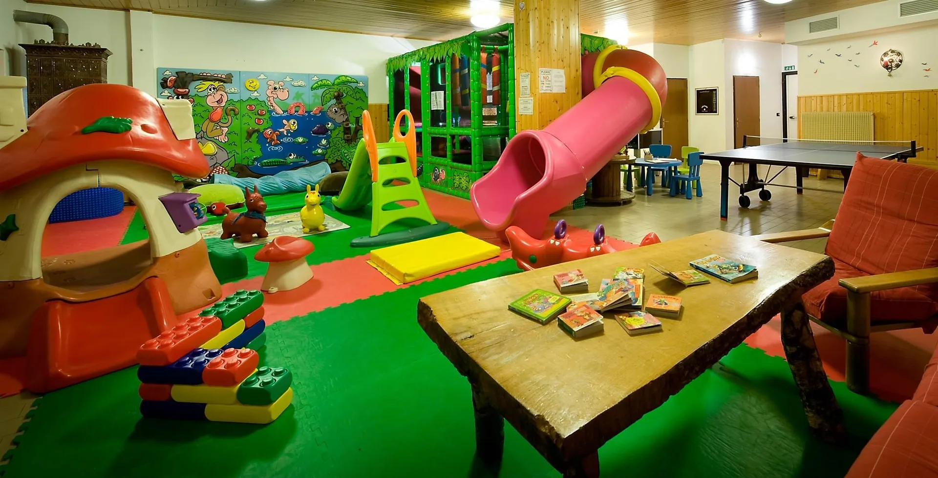 Sala giochi per bambini con scivolo, giocattoli e tavolo da ping pong