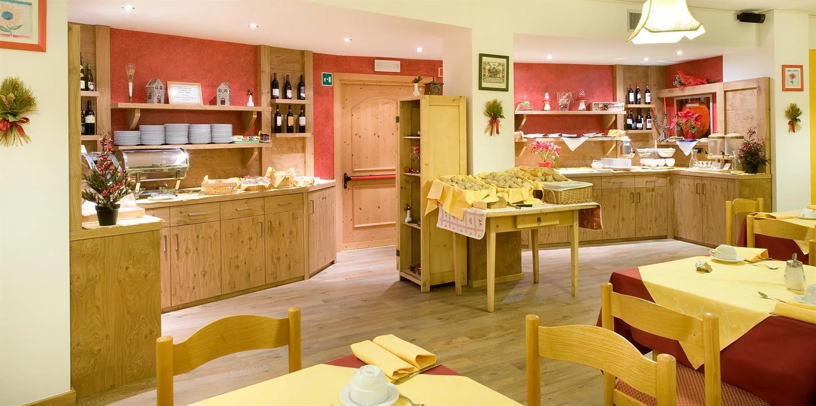 Sala colazione con buffet e arredi in legno chiaro e pareti rosse