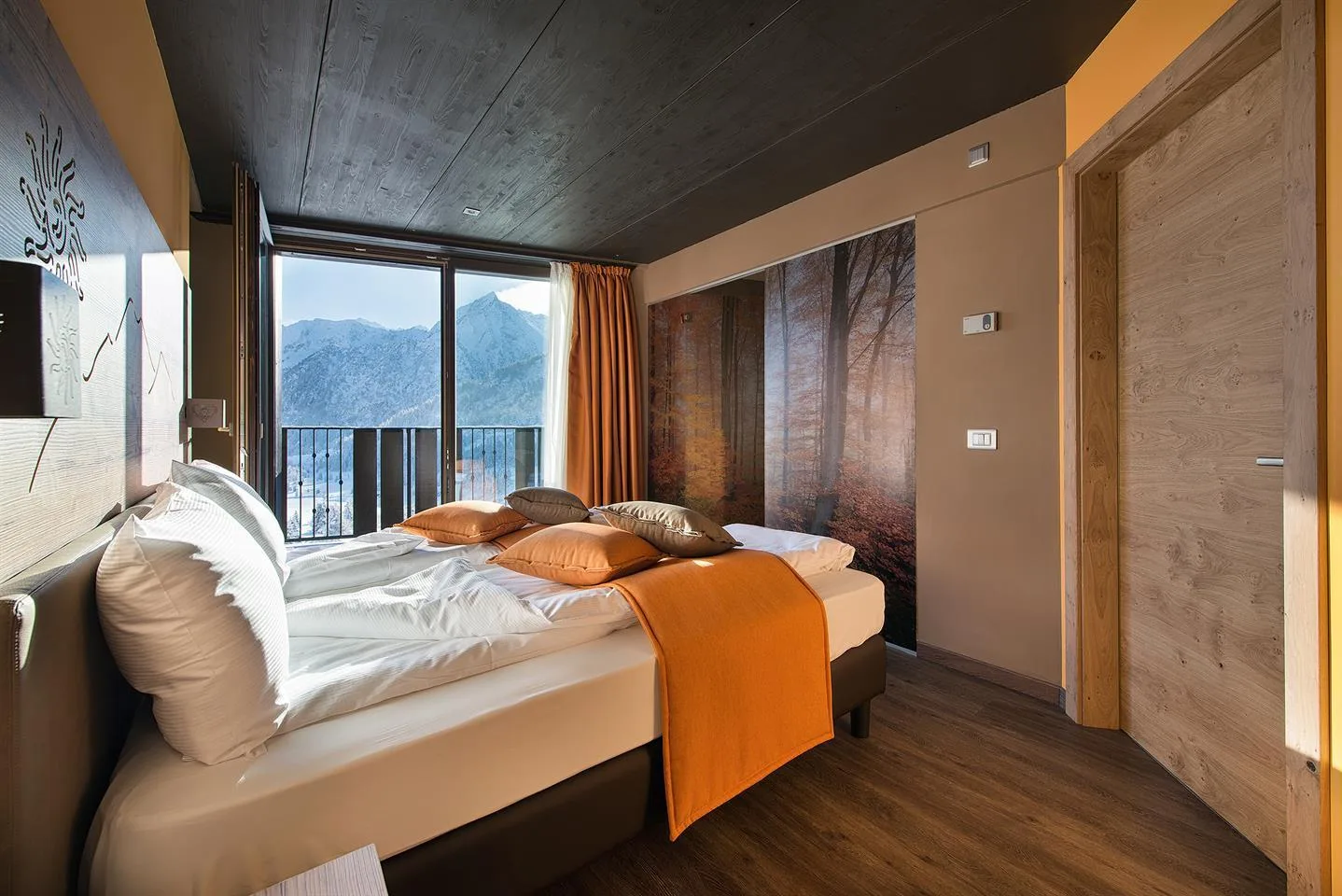 Camera moderna con letto matrimoniale e ampia finestra con vista montagna