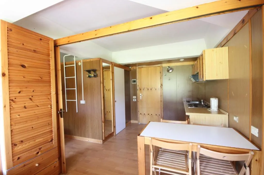 Interno di monolocale con angolo cottura in legno e tavolo con sedie