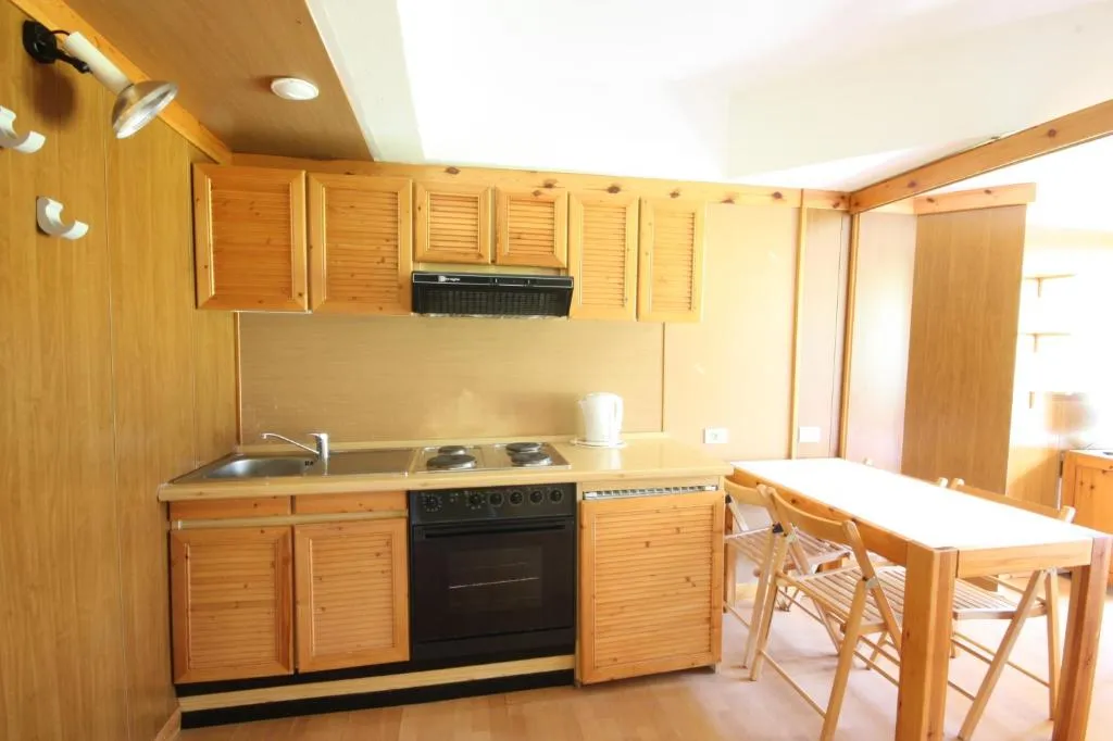 Angolo cottura in legno con lavello, piano cottura, forno e tavolo
