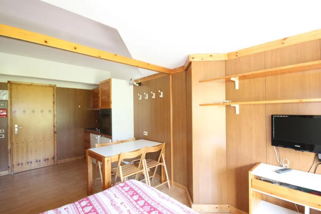 Interno di appartamento con zona pranzo, cucina, TV e boiserie in legno