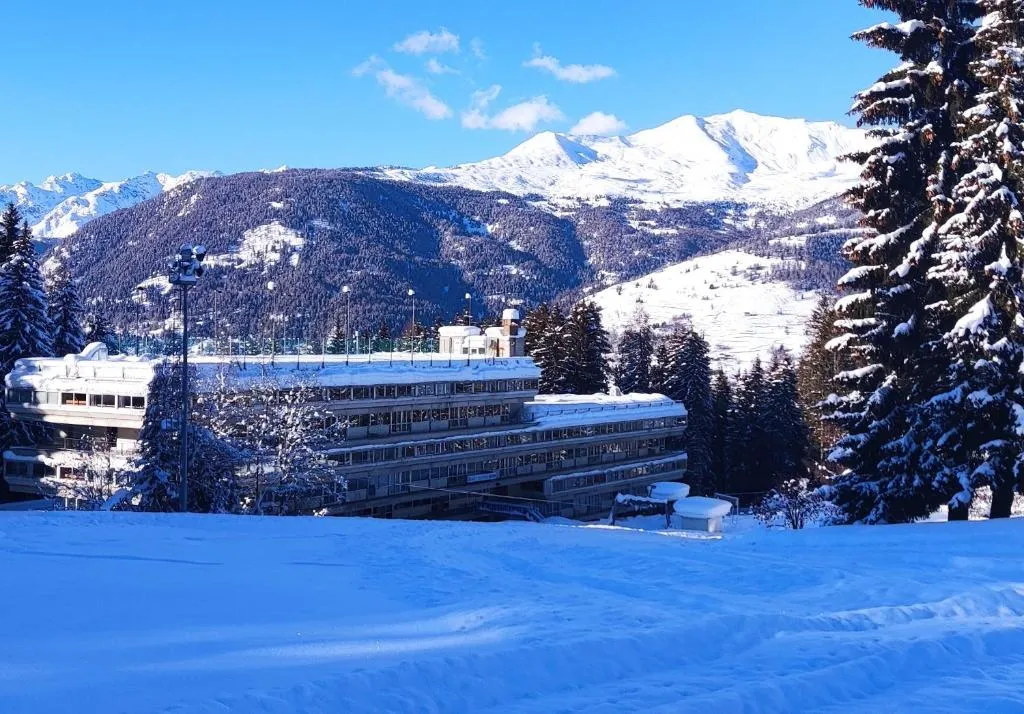 Vista invernale dell'hotel innevato con montagne e abeti coperti di neve