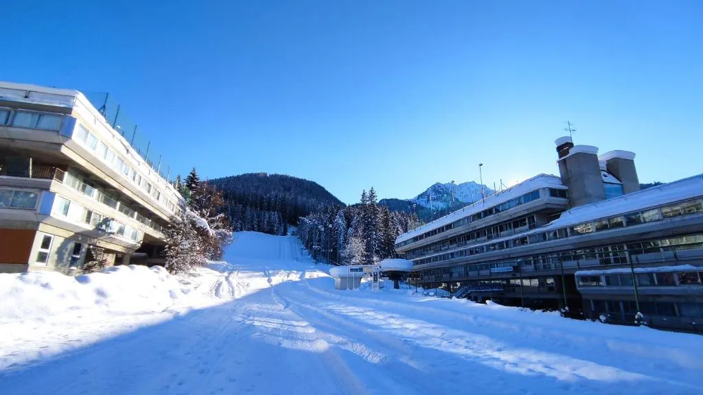Struttura alberghiera in inverno con neve e piste da sci tra le montagne