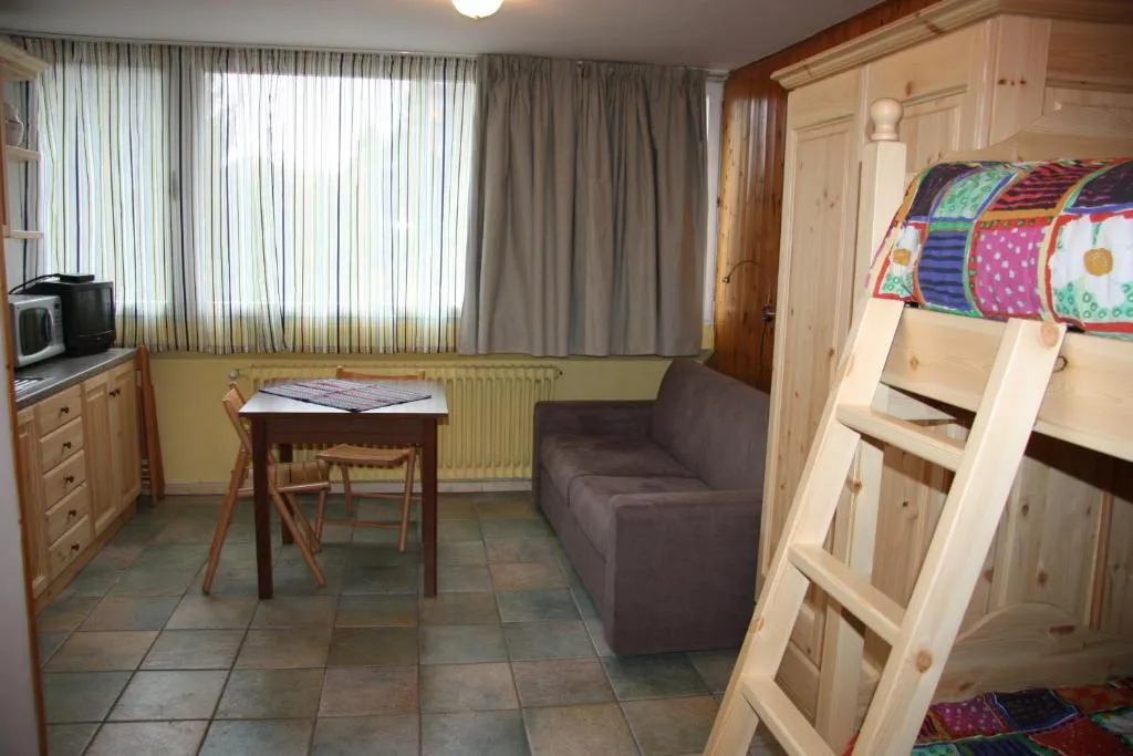 Soggiorno con letto a castello in pino, divano, tavolo e angolo cottura