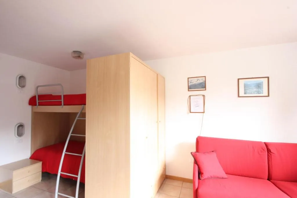 Monolocale con letto a castello rosso, armadio in legno e divano
