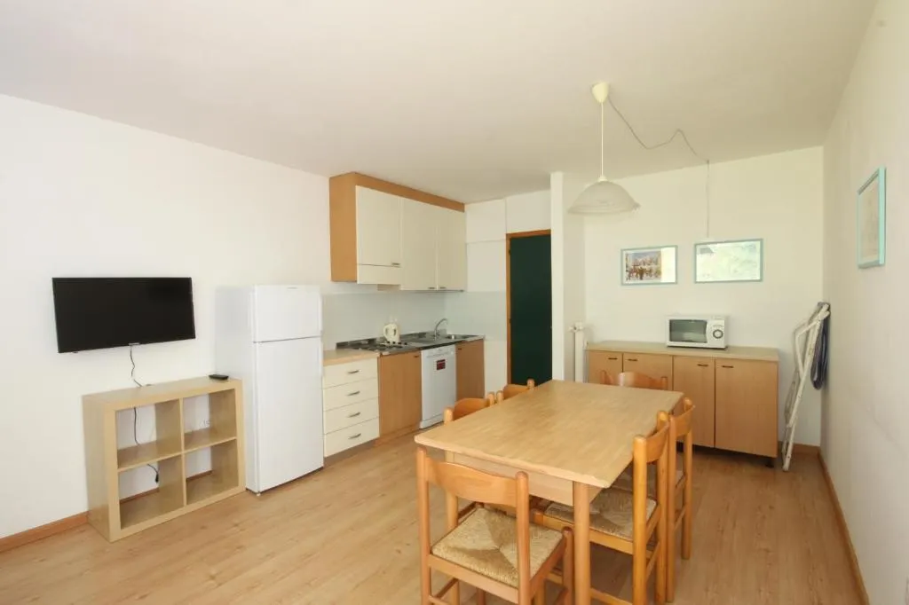 Appartamento con cucina attrezzata, frigorifero, tavolo in legno e TV a parete
