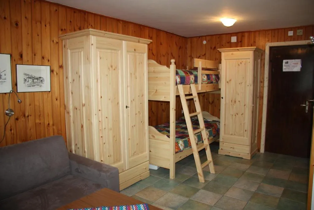 Camera rivestita in legno con letto a castello, armadi in pino e divano